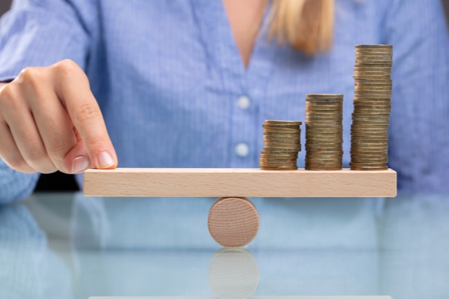 Affärskvinna balanserar högar med pengar med sitt finger