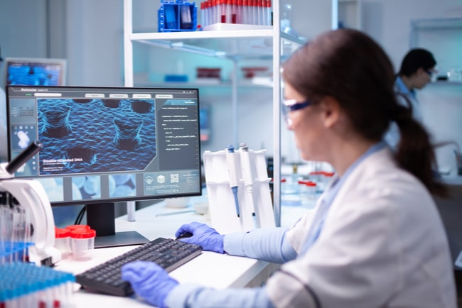 Forskare jobbar med bioteknik framför en skärm.